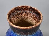 a close up of a blue and brown vase on a table