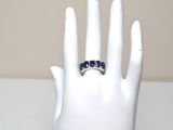 a white hand holding a ring with blue stones on it