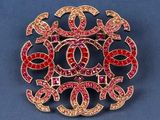 a close up of a brooch with red and pink stones