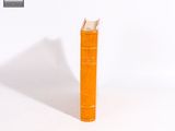 un livre orange posé sur une surface blanche
