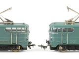 two green trains sitting side by side on a white surface