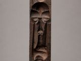 a carved wooden block with a face and two faces on it