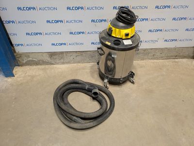 l'aspirateur se trouve à côté d'un tuyau, posée par terre devant un mur