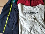 two jackets and a t - shirt are sitting on a cardboard box