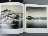 an open book with a black and white photo of rocks and water