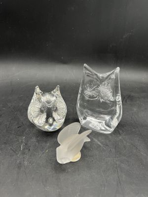 deux figurines en verre représentant des chats assis sur une surface noire
