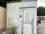 a white toilet sitting outside of a building next to a trash can