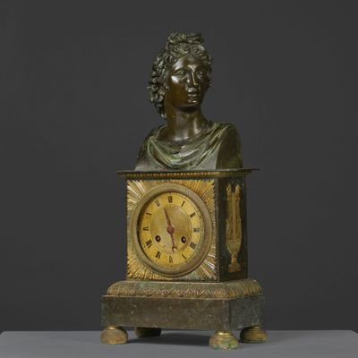 bronze bust of a man holding a clock with roman numerals on it