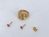 a gold ring with a cross on it next to a pair of studs