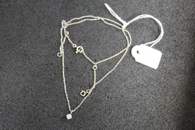 a close up of a silver necklace with a tag on it