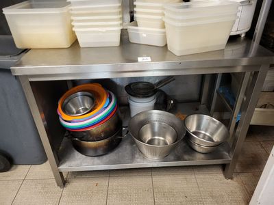 Plusieurs casseroles et poêles sont empilées sur une étagère en acier inoxydable