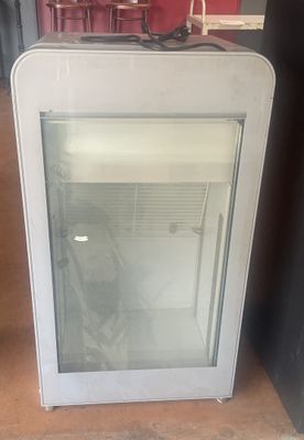 un petit réfrigérateur avec une porte vitrée dans une pièce
