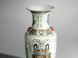 un vase blanc avec un tableau posé sur une table