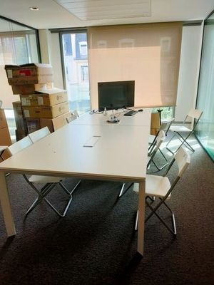 une table blanche avec des chaises et un ordinateur posé dessus