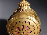 an antique gold clock with a red flower on the face