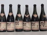six bottles of wine are lined up on a table