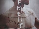 affiche représentant un homme avec des tatouages sur la poitrine et le mot « mementoe » inscrit sur sa poitrine
