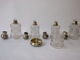 six glass bottles and a silver plate on a white surface