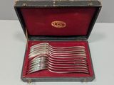des couverts dans un coffret à doublure rouge, posés sur une table