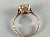 a close up of a gold ring with a green stone