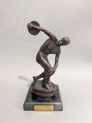 bronze statue of a man throwing a basketball ball on a marble base