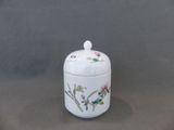 un petit pot blanc orné de fleurs, posé sur une table