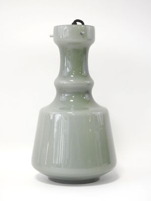 un vase vert avec une anse noire sur fond blanc