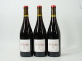 trois bouteilles de vin rouge posées l'une à côté de l'autre sur une surface blanche