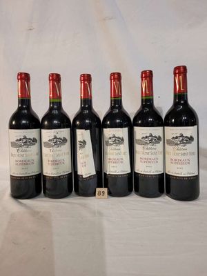 six bottles of red wine are lined up on a table