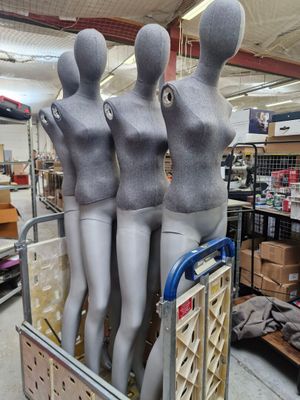 trois mannequins assis sur un chariot dans un magasin
