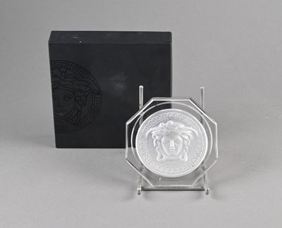 une assiette en argent ornée d'une tête de lion, à côté d'une boîte noire
