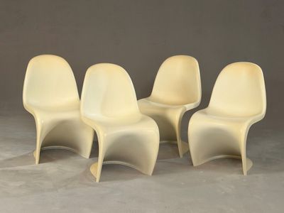quatre chaises en plastique blanches alignées les unes à côté des autres sur un sol en béton