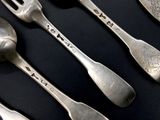 five silver spoons and a fork on a black table