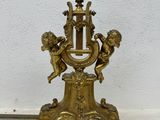 a gold clock on a stand with angels on it