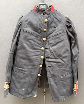 une veste grise à boutons dorés et col rouge, posée sur un présentoir pour mannequin