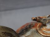 a close up of a teapot with a bird on top of it