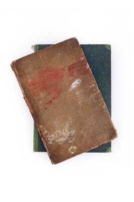 deux vieux livres sont empilés l'un sur l'autre sur une surface blanche