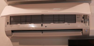 a white air conditioner sitting on a wall next to a television