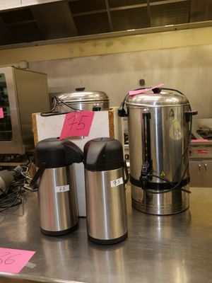 un plan de travail en acier inoxydable sur lequel sont posées deux cafetières et une machine à café