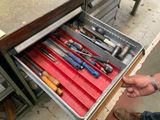 un tiroir rempli d'outils posé sur un établi dans un garage