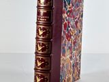 a red book with gold trim sitting on a white surface