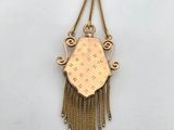 a close up of a gold necklace with fringes on a white surface
