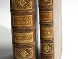 two old books are sitting side by side on a white surface