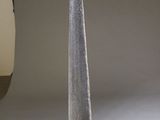 a tall silver object on a table in front of a gray backdrop