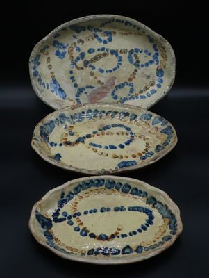 trois assiettes bleues et blanches ornées de motifs, posées sur un fond noir