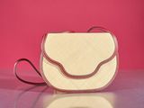 beige and red purse on a table against a pink background