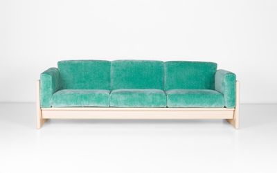 un canapé en velours vert adossé à un mur blanc dans une pièce blanche