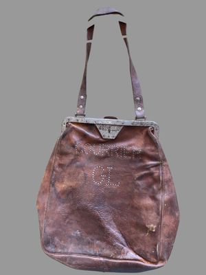 sac à main en cuir marron avec des anses cloutées sur fond gris