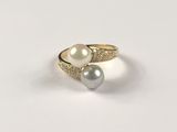 a close up of a ring with two pearls on it