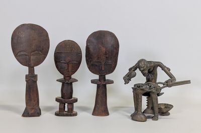 trois figurines en bois de formes et de tailles différentes posées sur une surface blanche
